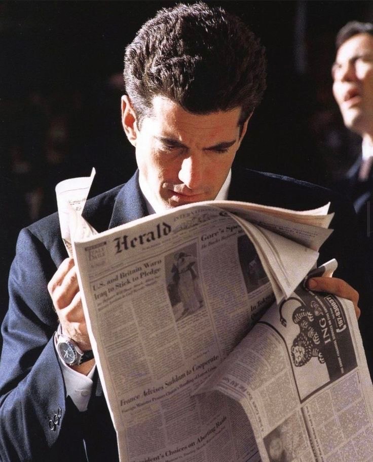 Man in a dark suit reading the International Herald Tribune.